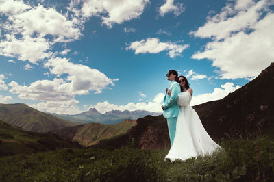 Young wedding couple together in the mountains. bride hugs groom, newlyweds in the mountains