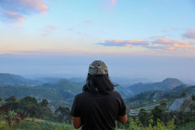 Rear view of man looking at mountain range against sky