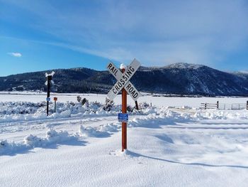 Scenic railroad view of snow covered field against sky