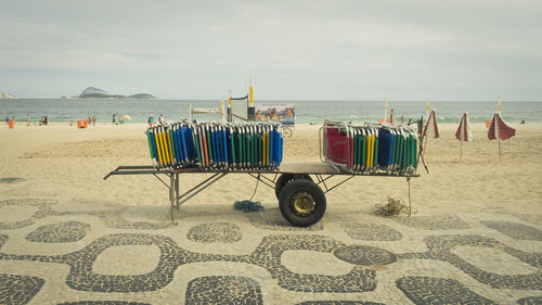 Deck chairs on beach against sky