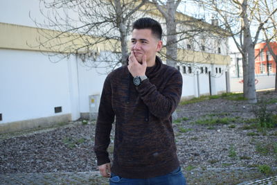 Portrait of young man standing against tree