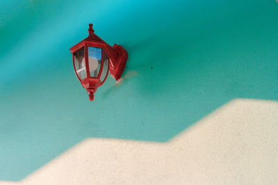 Red umbrella hanging on wall by swimming pool