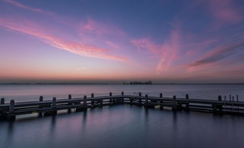 Pier over sea against sky during sunset