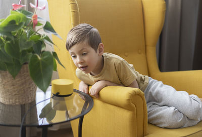 Portrait of cute boy sitting on sofa at home