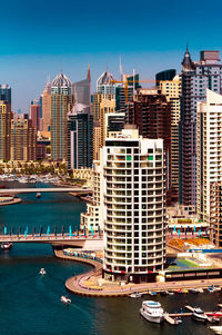 Buildings by canal against clear blue sky