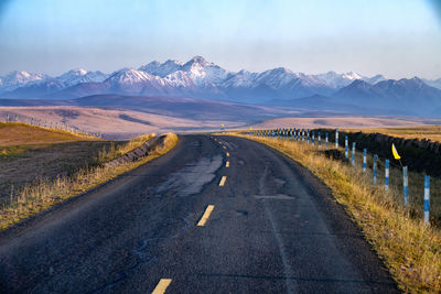 Road amidst snowcapped mountains against sky