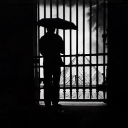 Silhouette man standing against window at home