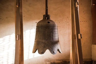 Low angle view of old bell hanging against wall