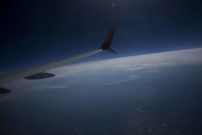 Close-up of airplane flying over sea against blue sky