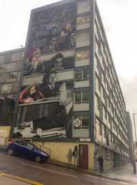 Low angle view of vehicles on road against buildings