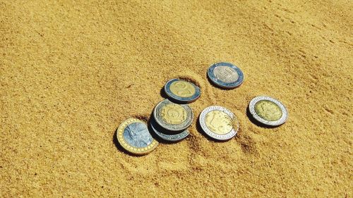 High angle view of coins on sand