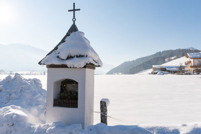 The mountain chapel with cross covered with wooden shingle. snow-capped mountains, blue sky