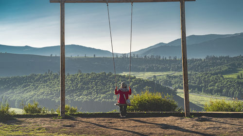 Rear view of woman standing on field against mountain