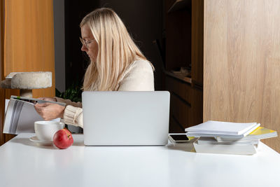 Midsection of woman using smart phone while sitting on table