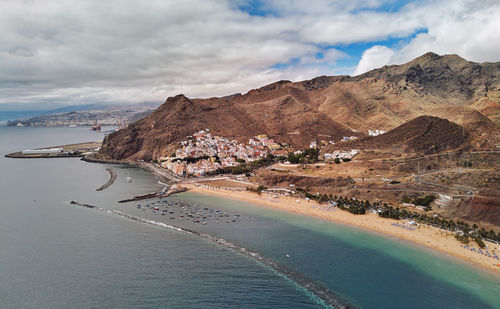 Aerial view of city by sea against sky