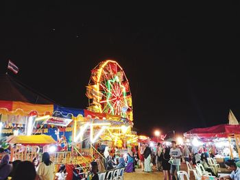 People in illuminated amusement park at night