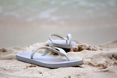 Close-up of shoes on beach