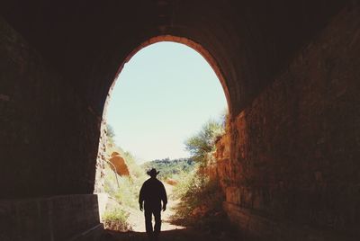 Rear view of silhouette man standing in front of tunnel