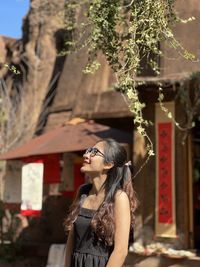 Portrait of smiling young woman standing against trees