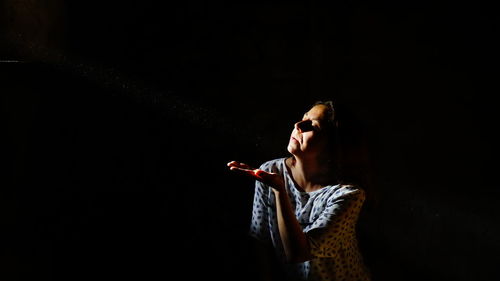 Woman gesturing against black background