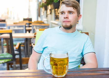 Portrait of young man sitting on table at restaurant