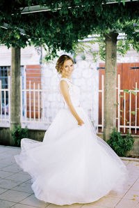 Portrait of young woman standing on footpath