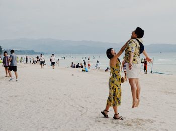 Friends standing on beach against sky