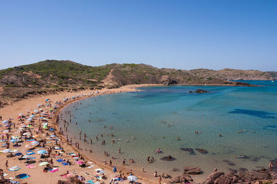 People on beach against clear blue sky