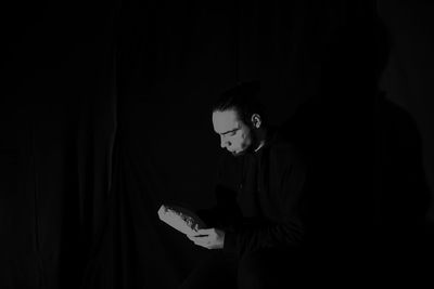 Full length of young man sitting in darkroom