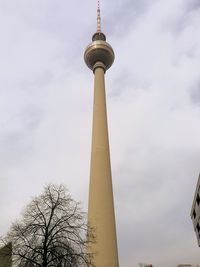 Low angle view of communications tower against cloudy sky