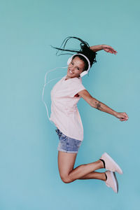 Woman with arms raised against blue background