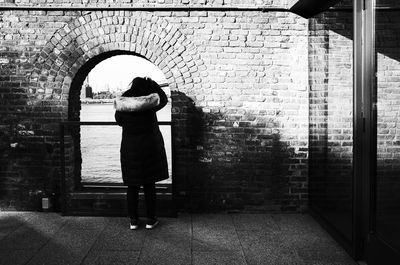 Rear view of woman standing against wall