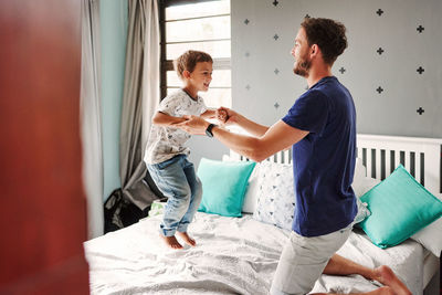 Father playing with son on bed at home