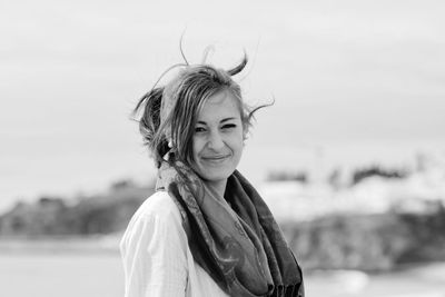 Portrait of smiling woman standing against sky