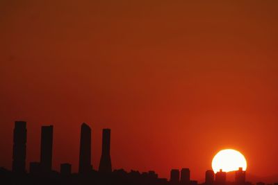 Silhouette buildings against orange sky