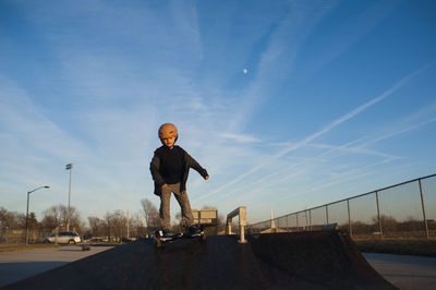 Young boy in helmet riding down pyramid ramp at skate park