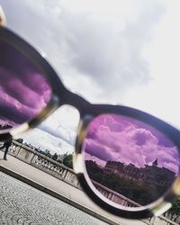 Close-up of sunglasses on mirror against sky