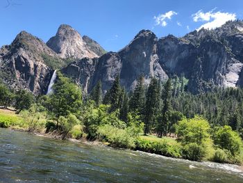 Scenic view of river by mountains against sky