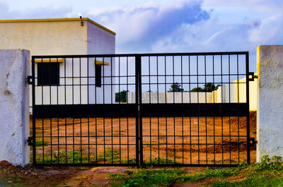 Building seen through metal fence against sky