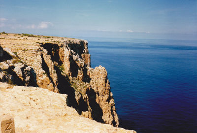 Scenic view of cliff by sea against sky