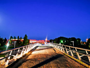 Illuminated bridge against blue sky in city at night