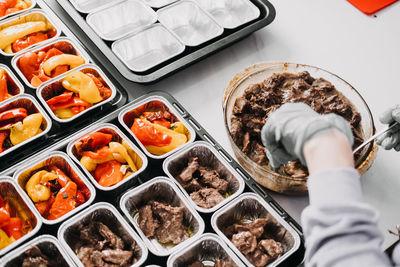 Caterer in a professional kitchen preparing individual servings of roasted vegetables