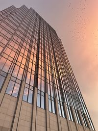 Low angle view of skyscraper against sky during sunset
