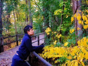 Portrait of young man standing amidst plants in forest