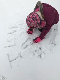 High angle view of child playing on snow covered field