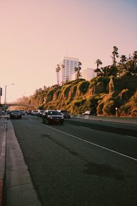 Cars on road against sky at sunset