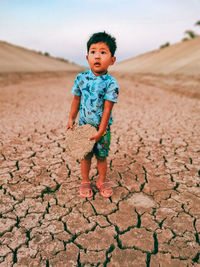 Full length of cute boy standing on dirt road