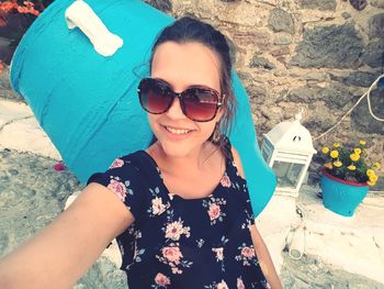 Portrait of smiling young woman wearing sunglasses standing at beach