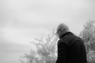 Man standing by tree against sky