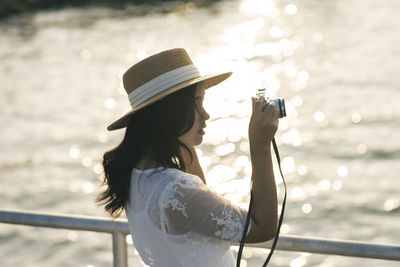Reflection of woman photographing water on railing